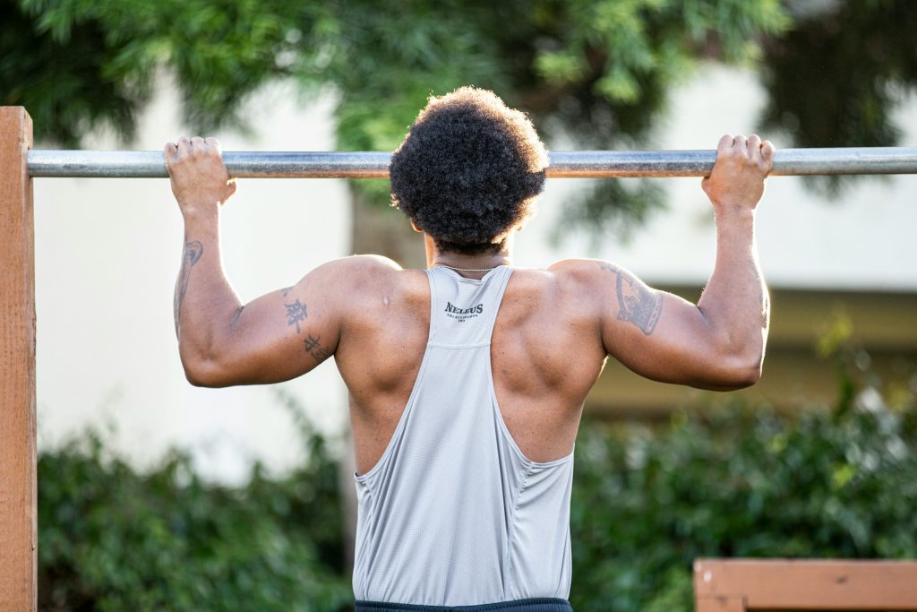 man in gray tank top holding gray metal bar